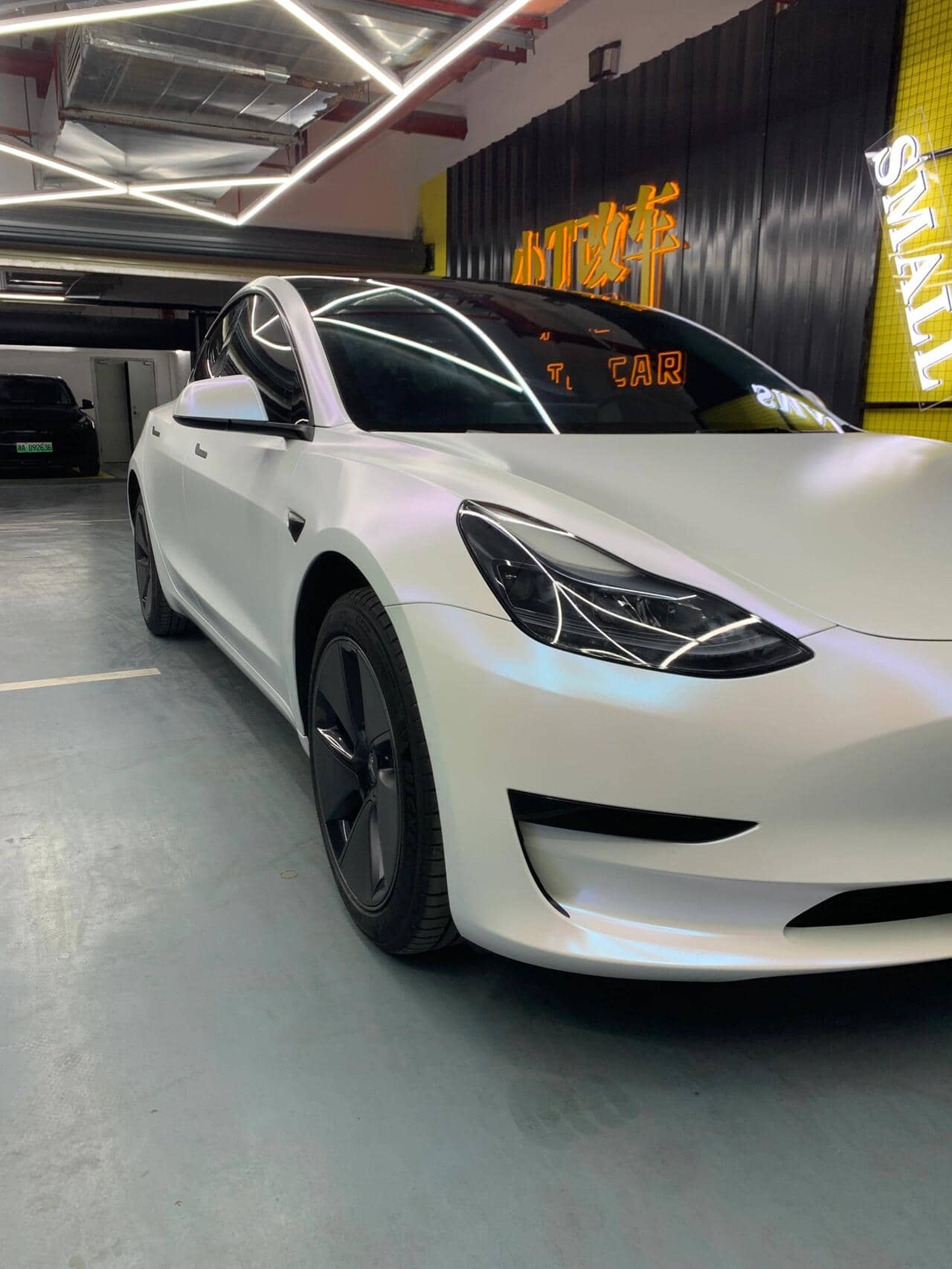 Tesla Model 3 featuring a matte white tesla wrap by WrapBug in a showroom setting