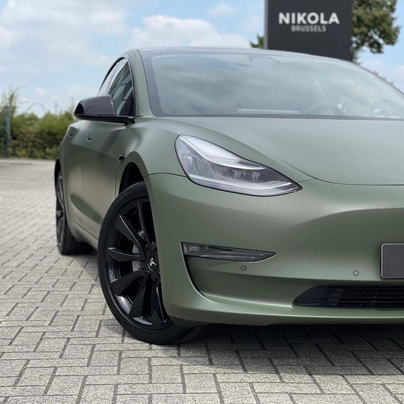 Tesla Model 3 electric car with matte green WrapBug vinyl wrap and black alloy wheels