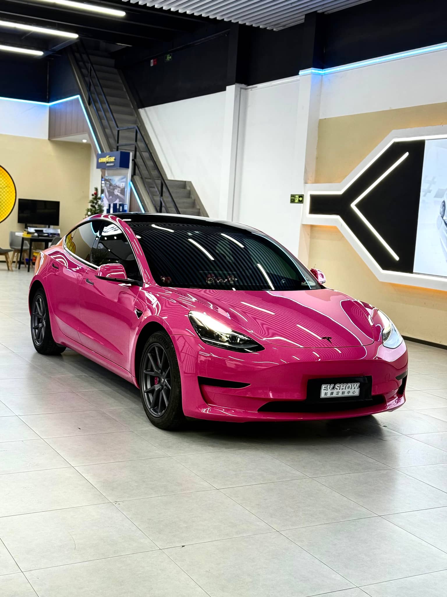 Pink Tesla Model 3 wrapped with WrapBug Pre-cut Tesla Vinyl Wrap in a showroom