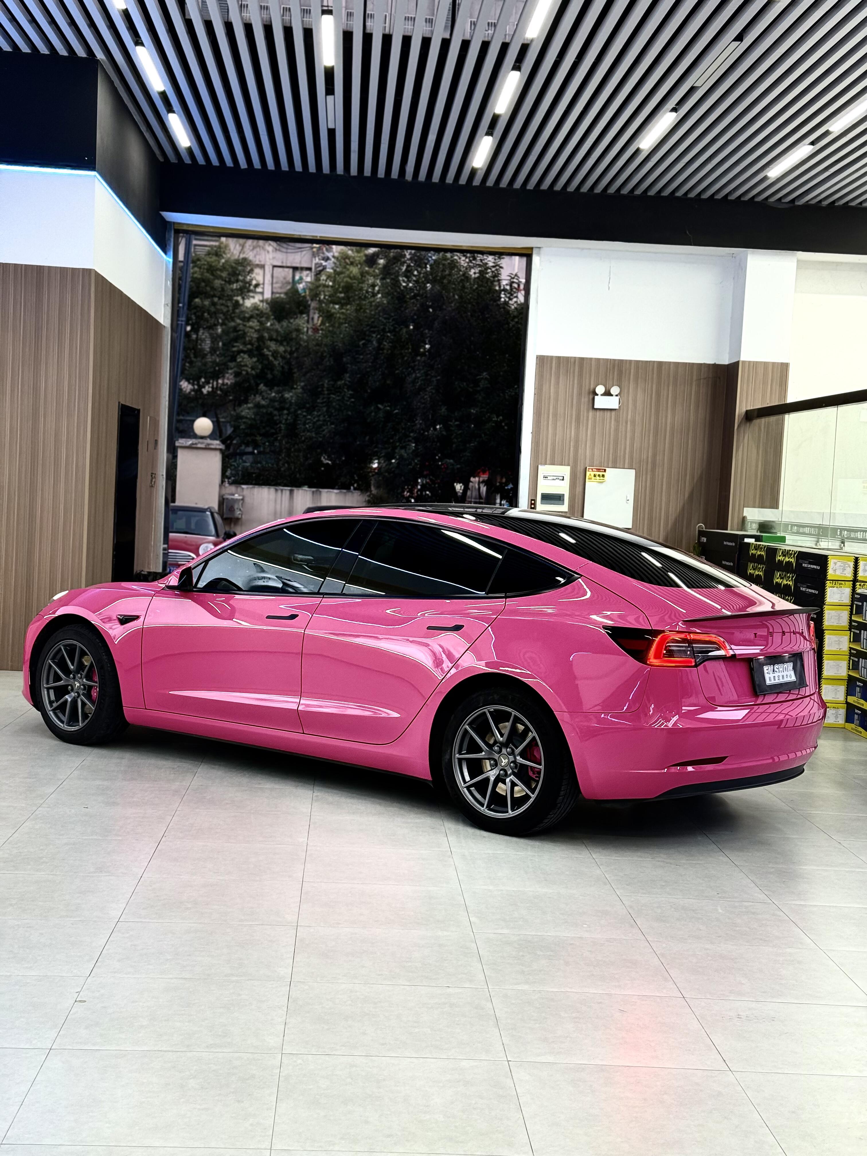 Tesla car wrapped in bright pink Pre-cut Tesla Vinyl Wrap parked indoors