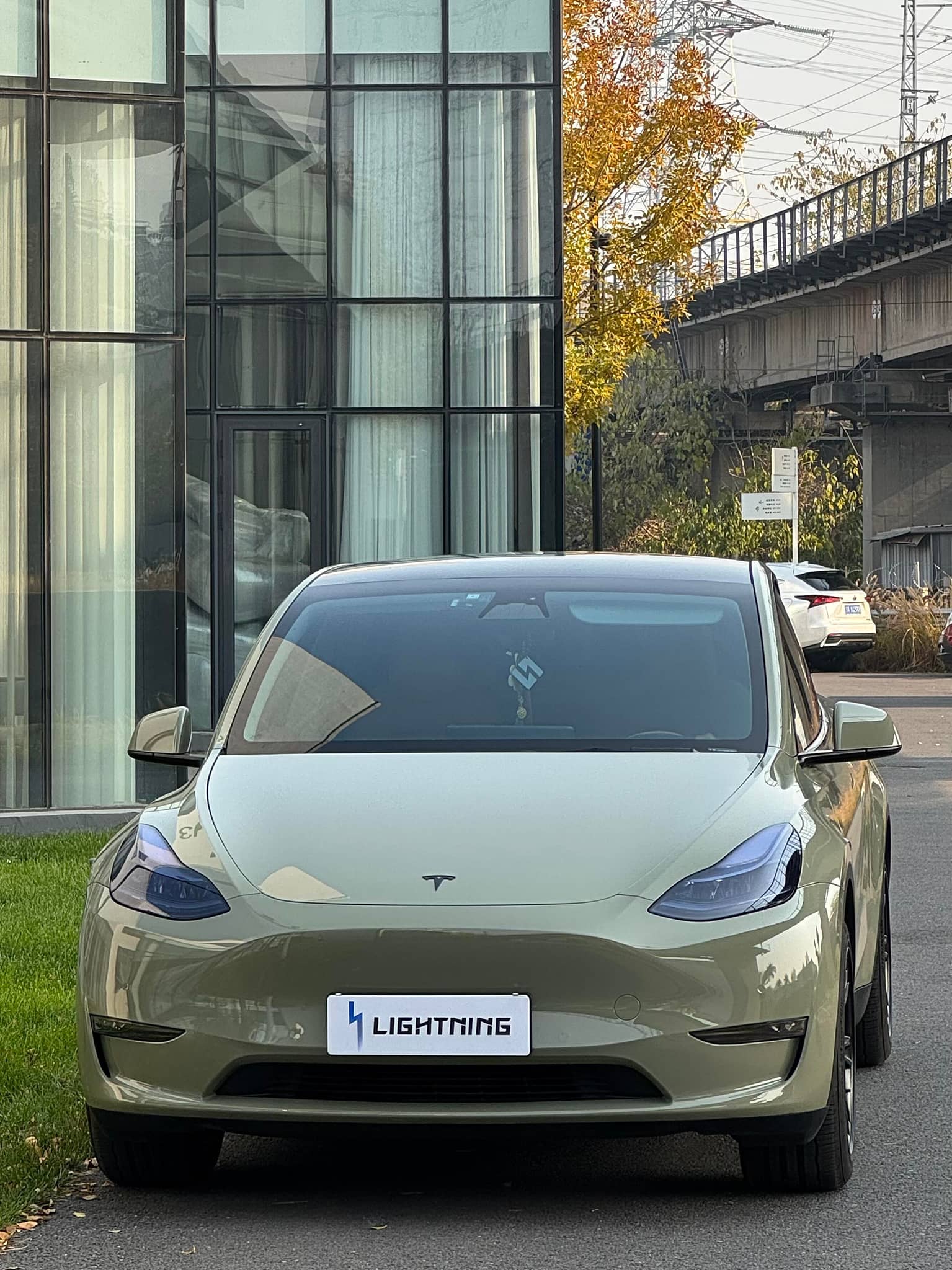 Tesla Model 3 with olive green pre-cut Tesla vinyl wrap kit parked in urban setting