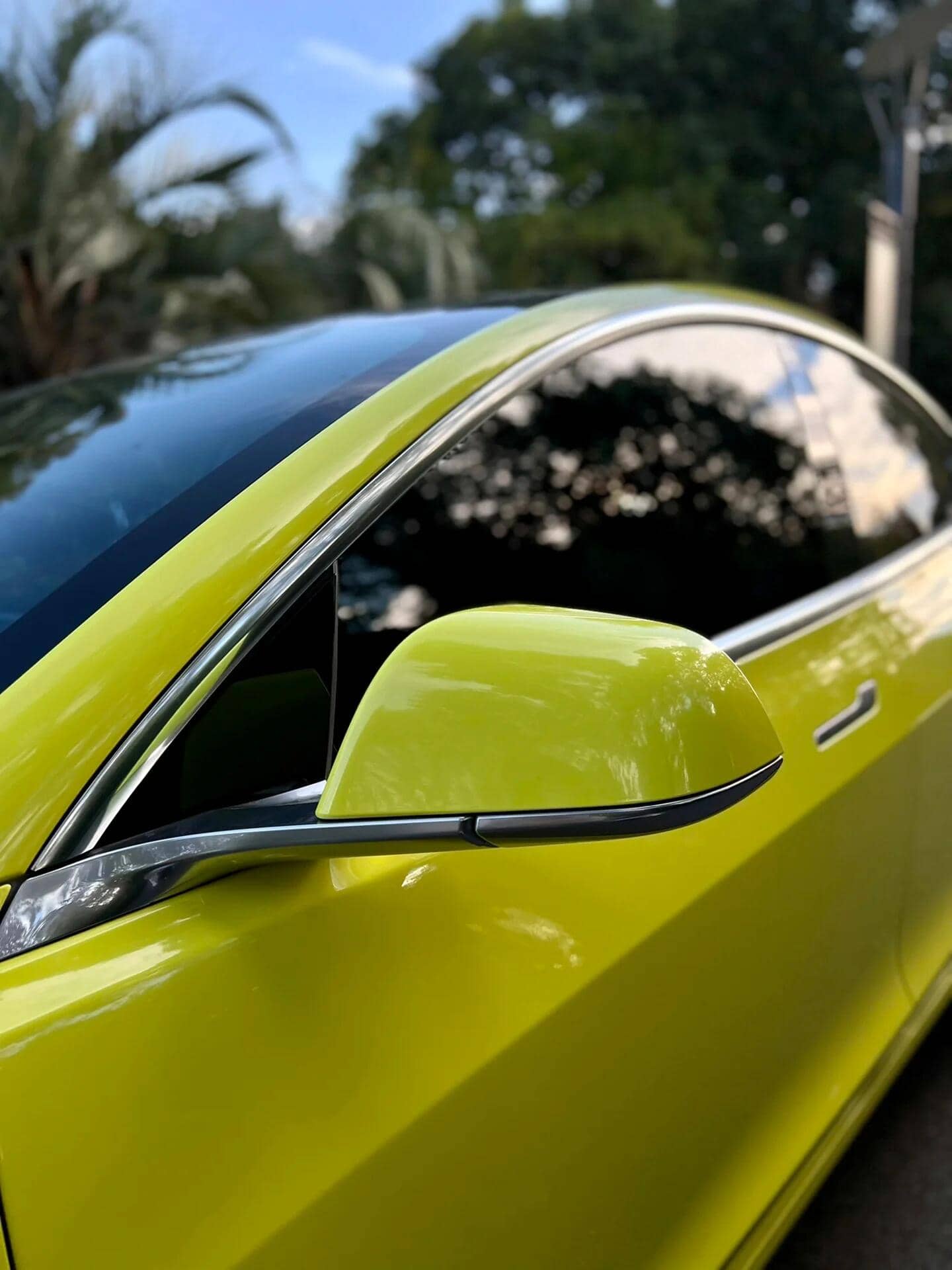 Close-up of yellow Tesla with Pre-cut Tesla Vinyl Wrap Kit applied on side mirror and door panel