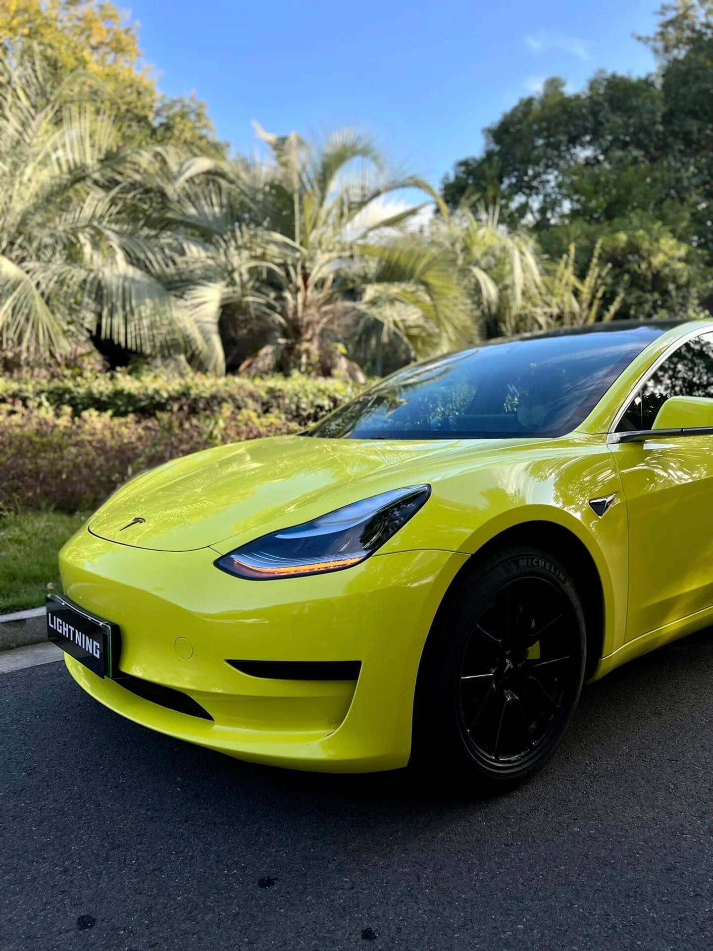 Bright yellow Tesla Model 3 featuring a Pre-cut Tesla Vinyl Wrap Kit on a sunny day