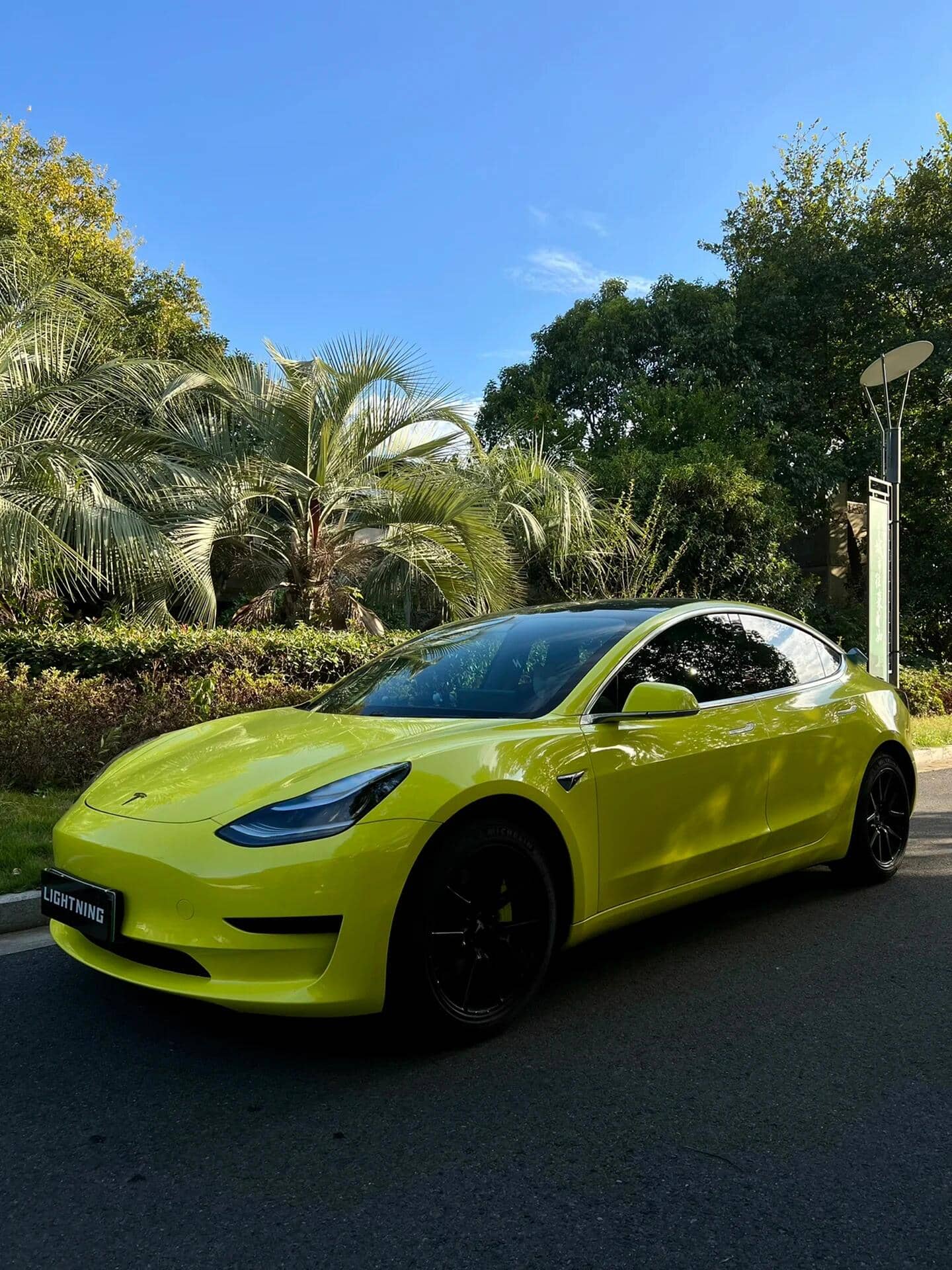 Yellow Tesla car wrapped using Pre-cut Tesla Vinyl Wrap Kit parked outdoors near palm trees