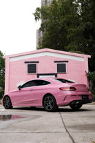 Pink luxury car wrapped with Pre-cut Tesla Wrap Kit parked in front of a pink building