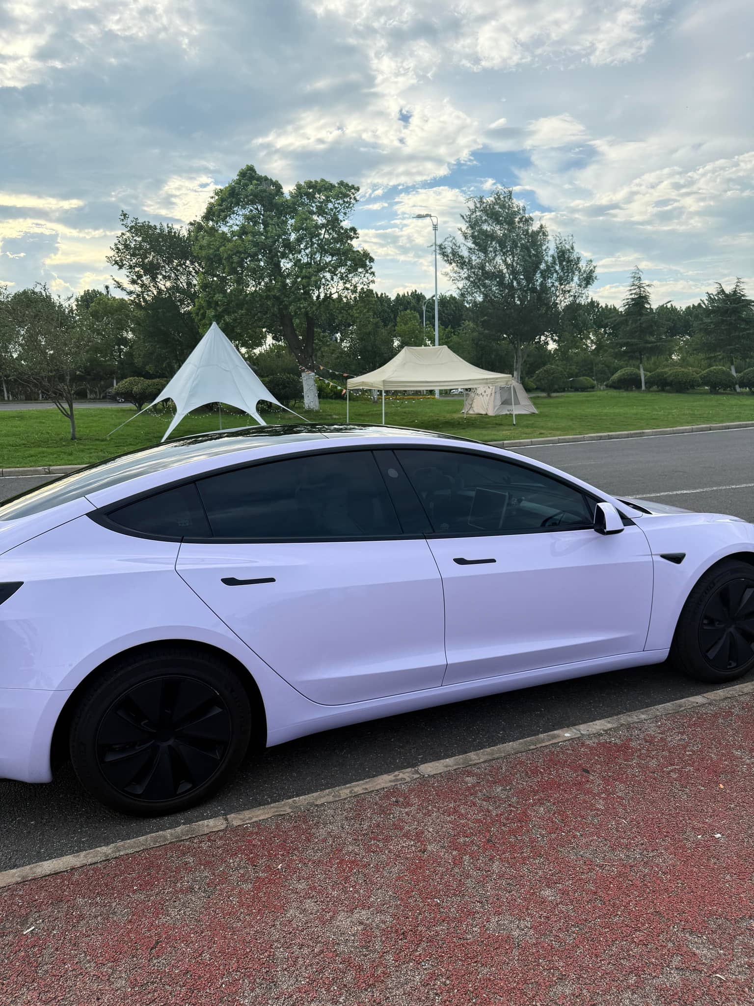 White Tesla Model 3 with Pre-cut Tesla Wrap Kit applied parked beside a road in daylight