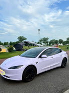 White Tesla Model 3 with WrapBug pre-cut Tesla wrap kit installed on a road near a park