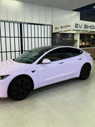 White Tesla Model 3 wrapped with a Pre-cut Tesla Wrap Kit displayed in modern EV showroom