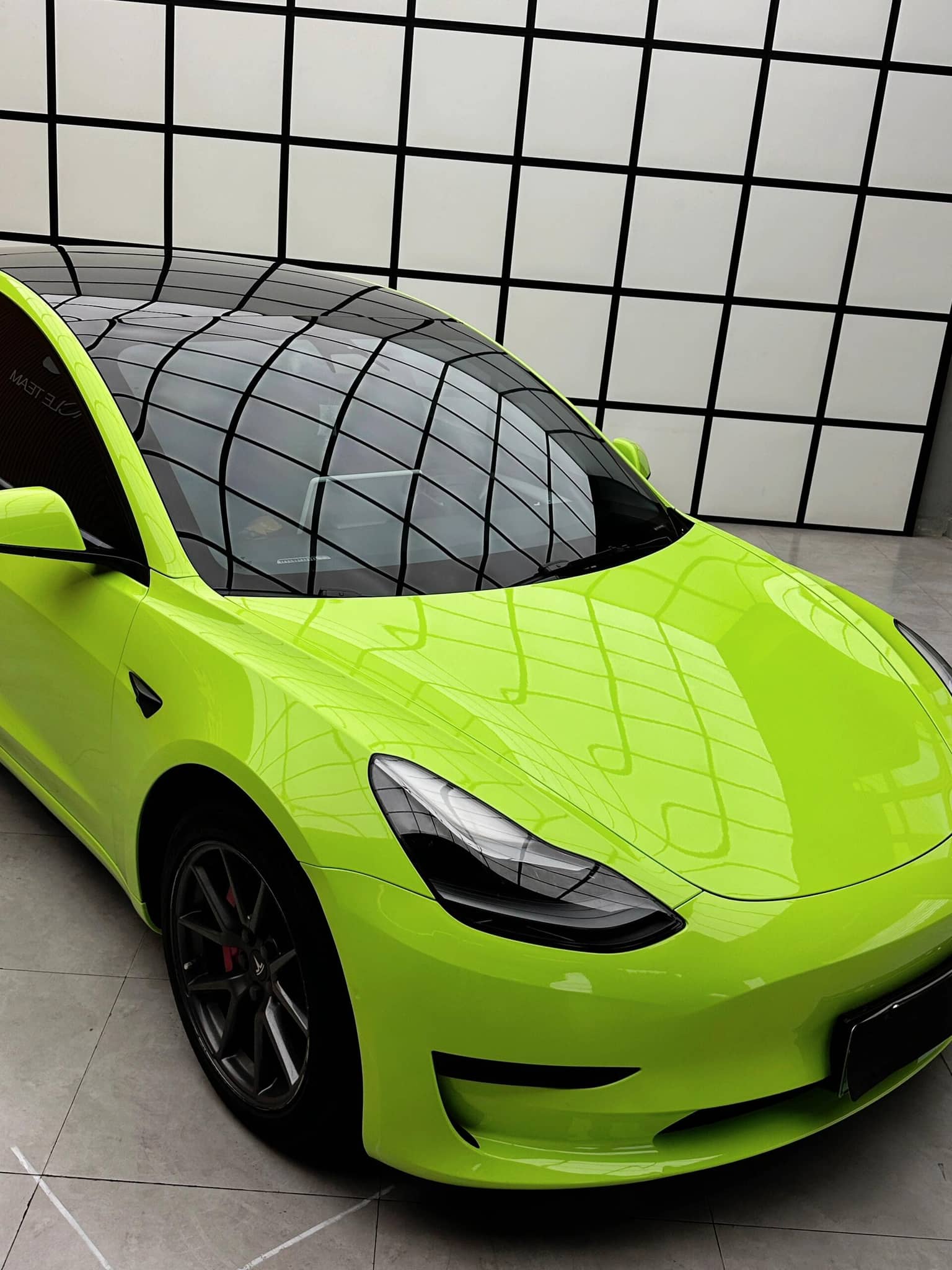Bright green Tesla with glossy finish using Pre-cut Tesla Wrap Kit by WrapBug in modern showroom