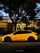 Yellow Tesla Model Y wrapped using Pre-cut Tesla Wrap Kit by WrapBug parked at night under trees