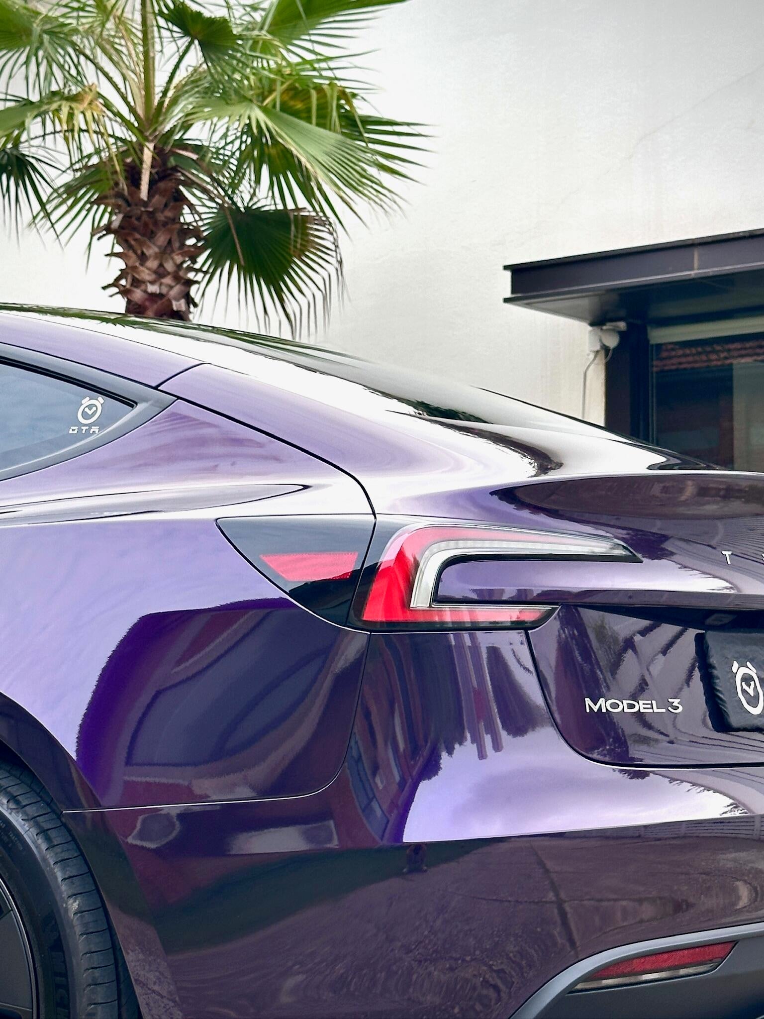 Glossy purple Tesla Model Y rear with Pre-cut Tesla Wrap Kit by WrapBug applied under palm trees