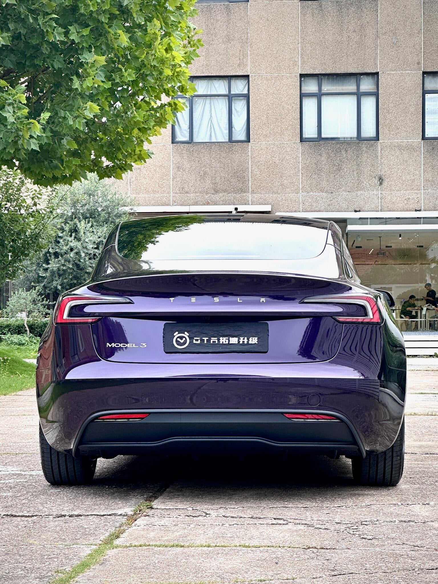 Rear view of a Tesla Model 3 wrapped in a glossy dark purple color using a Pre-cut Tesla Wrap Kit by WrapBug