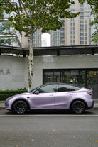 Tesla Model Y wrapped in a matte purple using a Pre-cut Tesla Wrap Kit by WrapBug parked on city street