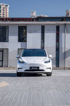 White Tesla Model Y parked in front of building featuring Pre-cut Tesla Wrap Kit by WrapBug
