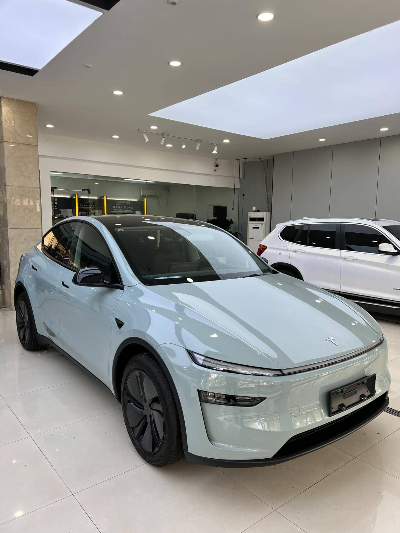 Light blue Tesla SUV with tesla color PPF protective film in a modern showroom