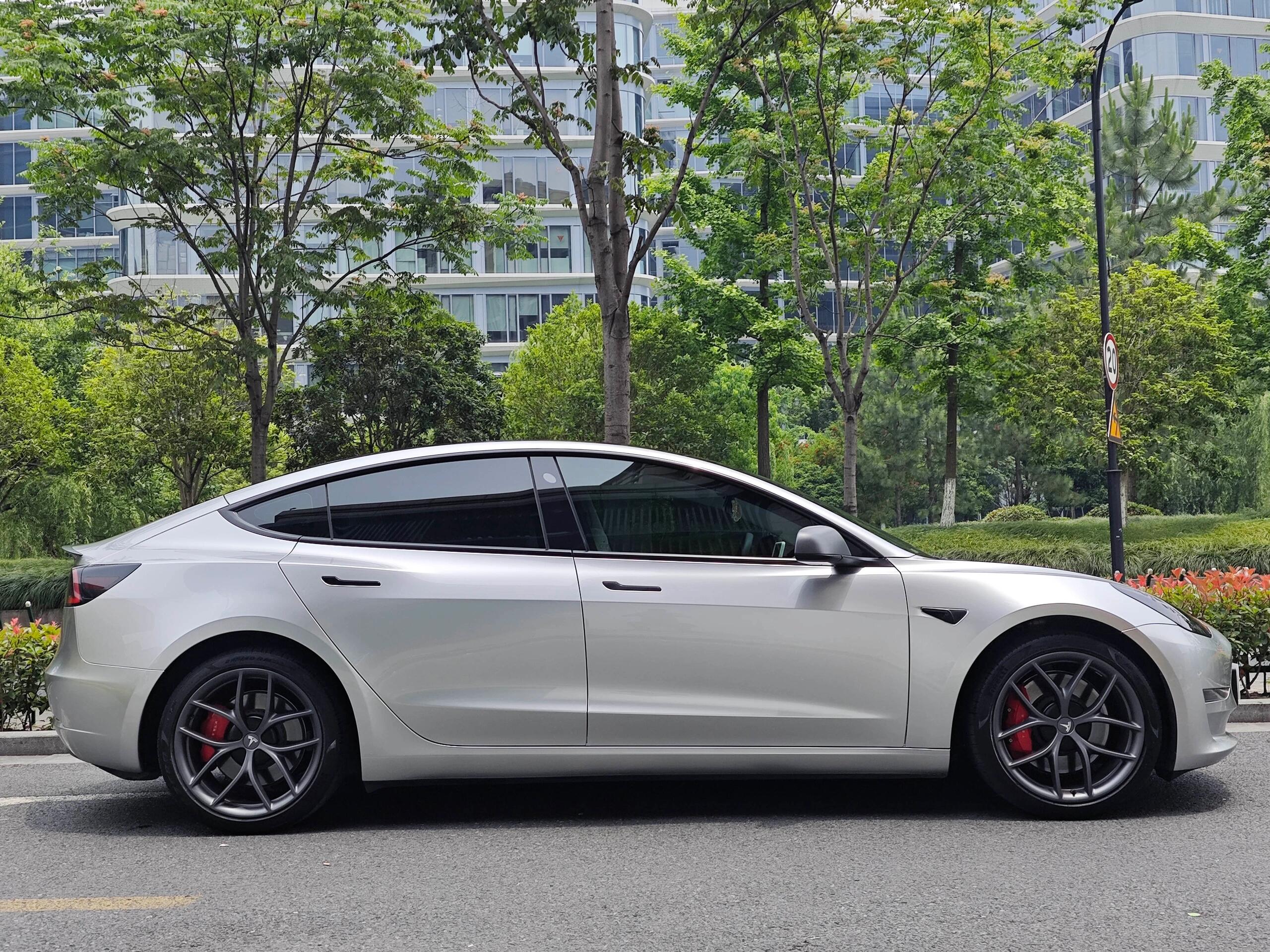 White Tesla sedan wrapped with WrapBug Pre-cut Tesla Wrap Kit parked on city street