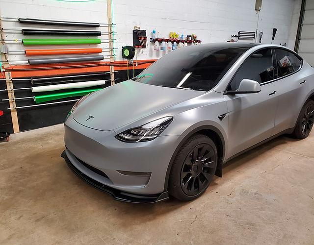 Tesla Model 3 wrapped in matte silver gray tesla model 3 wrap parked in garage with tool racks