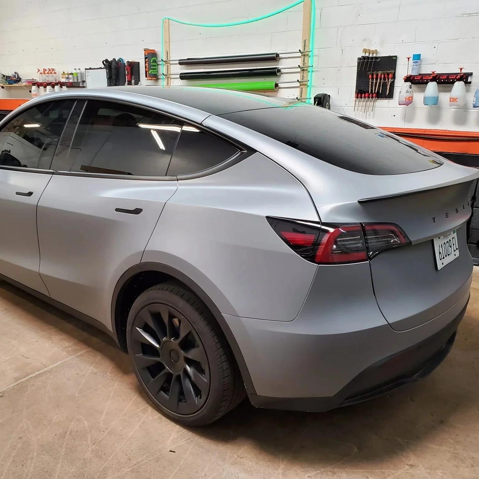 Matte gray tesla model 3 wrap installed on a Tesla Model 3 with tinted windows in a garage