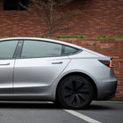 Silver Tesla Model 3 with matte finish parked beside brick wall featuring tesla model 3 wrap