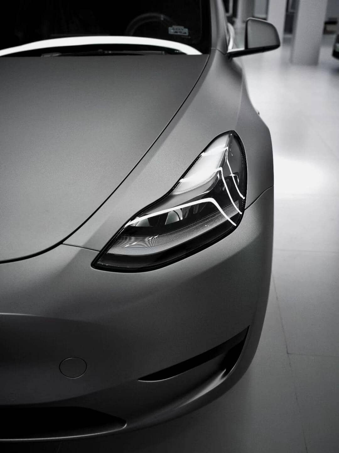 Close-up of a sleek gray car headlight with matte finish wrap by WrapBug