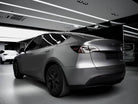 Tesla Model Y electric car in matte gray finish parked indoors under bright ceiling lights