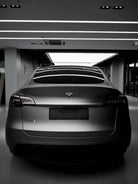 Rear view of a matte black Tesla Model X parked indoors under bright ceiling lights