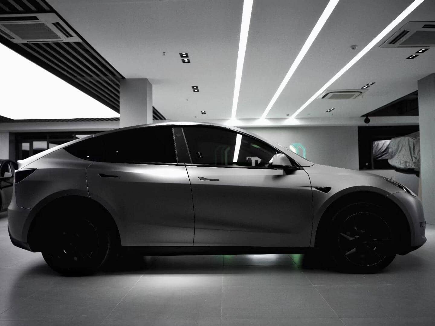 Matte black Tesla Model Y electric SUV parked indoors with tinted windows and black wheels