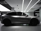 Matte black Tesla Model Y electric SUV parked indoors with tinted windows and black wheels
