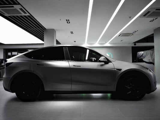 Matte black Tesla Model Y electric SUV parked indoors with tinted windows and black wheels