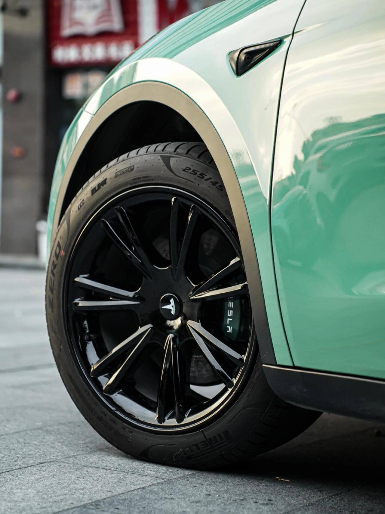 Close-up of Tesla car wheel with black rim and green body featuring Pre-cut Tesla Vinyl Wrap Kit