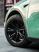 Close-up of Tesla car wheel with black rim and green body featuring Pre-cut Tesla Vinyl Wrap Kit