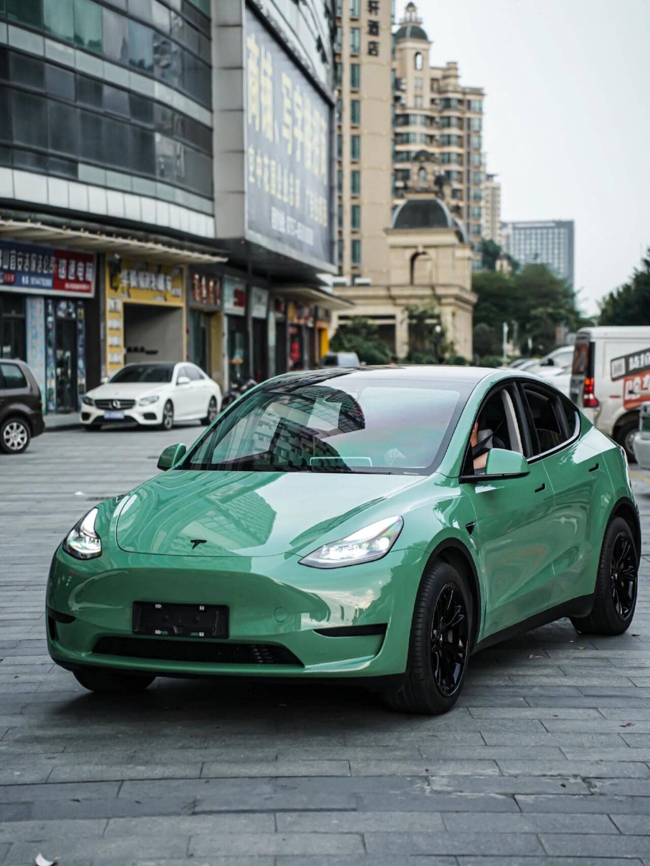 Tesla Model Y with green pre-cut Tesla vinyl wrap kit parked on city street by WrapBug