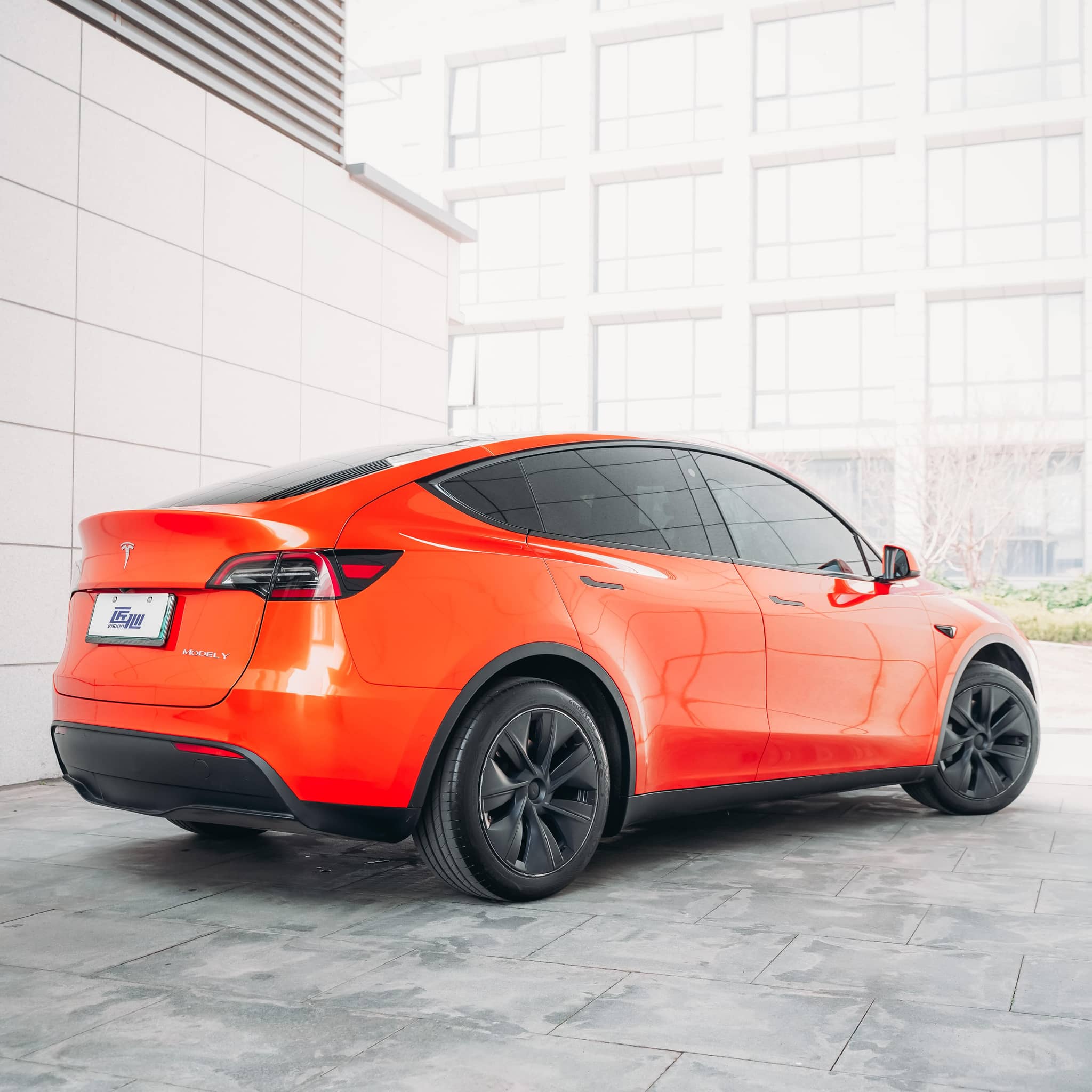 Orange Tesla Model Y wrapped using Pre-cut Tesla Wrap Kit by WrapBug with sleek black wheels and tinted windows