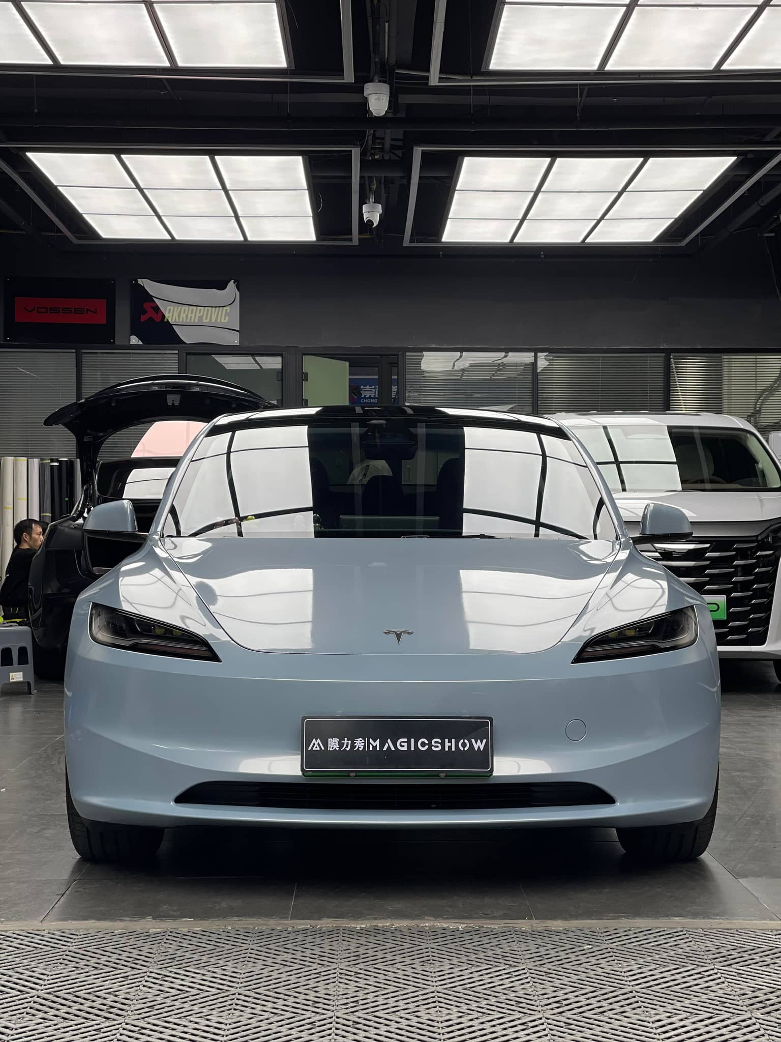 Front view of sleek silver Tesla Model X electric car with WrapBug branding in a showroom