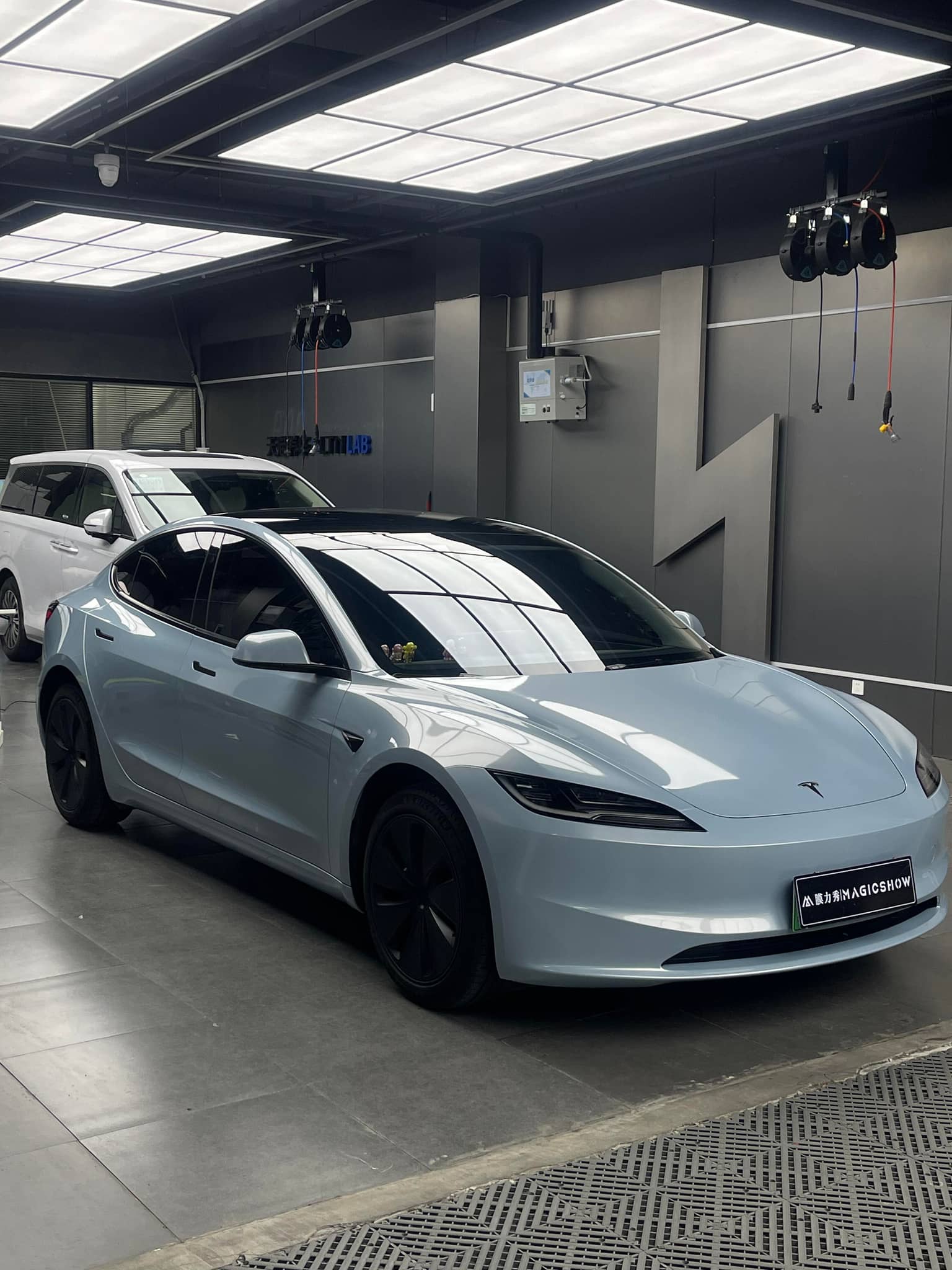 White Tesla Model S parked indoors with glossy finish under bright ceiling lights