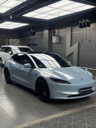 White Tesla Model S parked indoors with glossy finish under bright ceiling lights