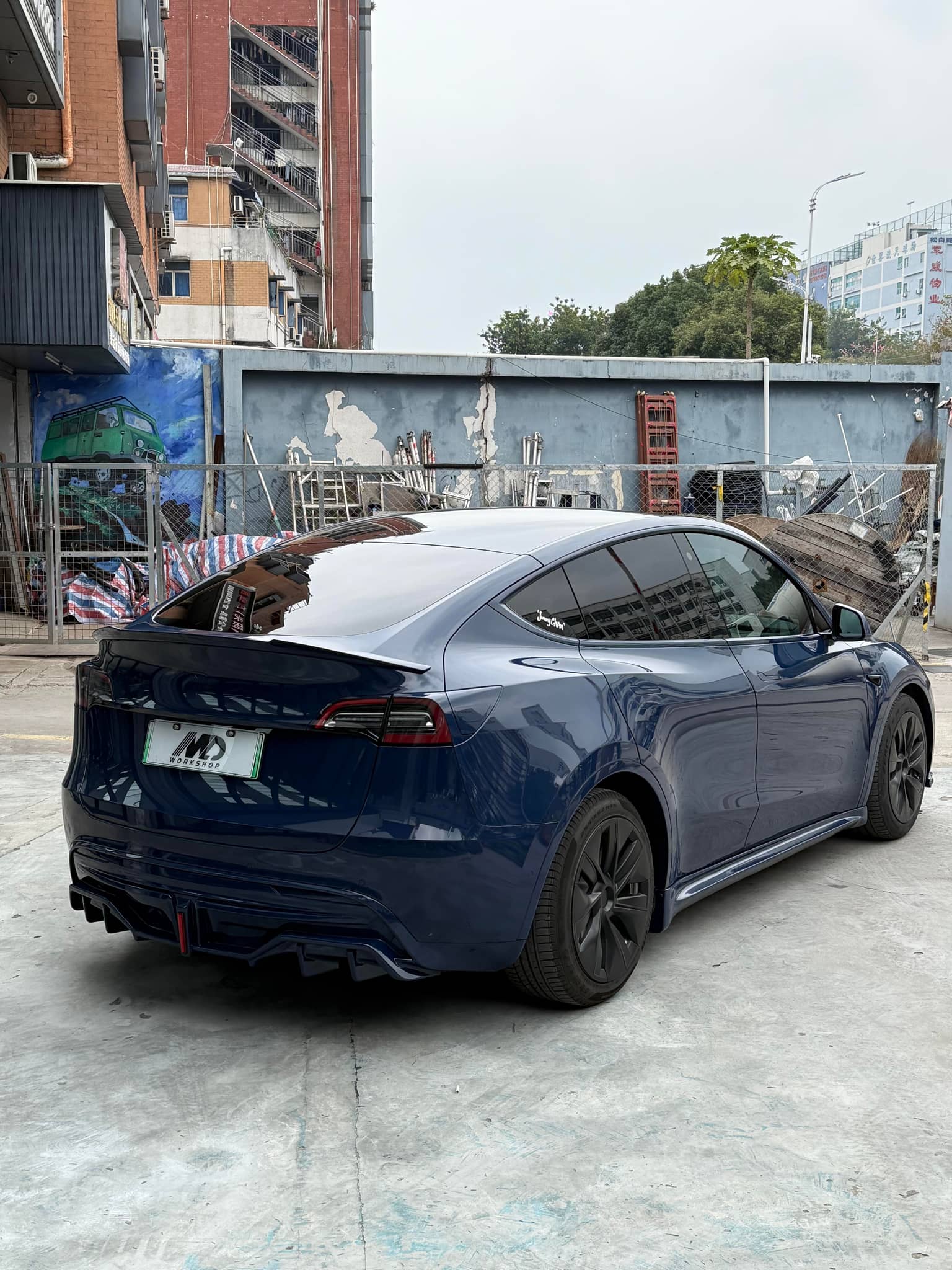 Dark blue Tesla Model Y with glossy finish using WrapBug Pre-cut Tesla Vinyl Wrap Kit parked in urban area