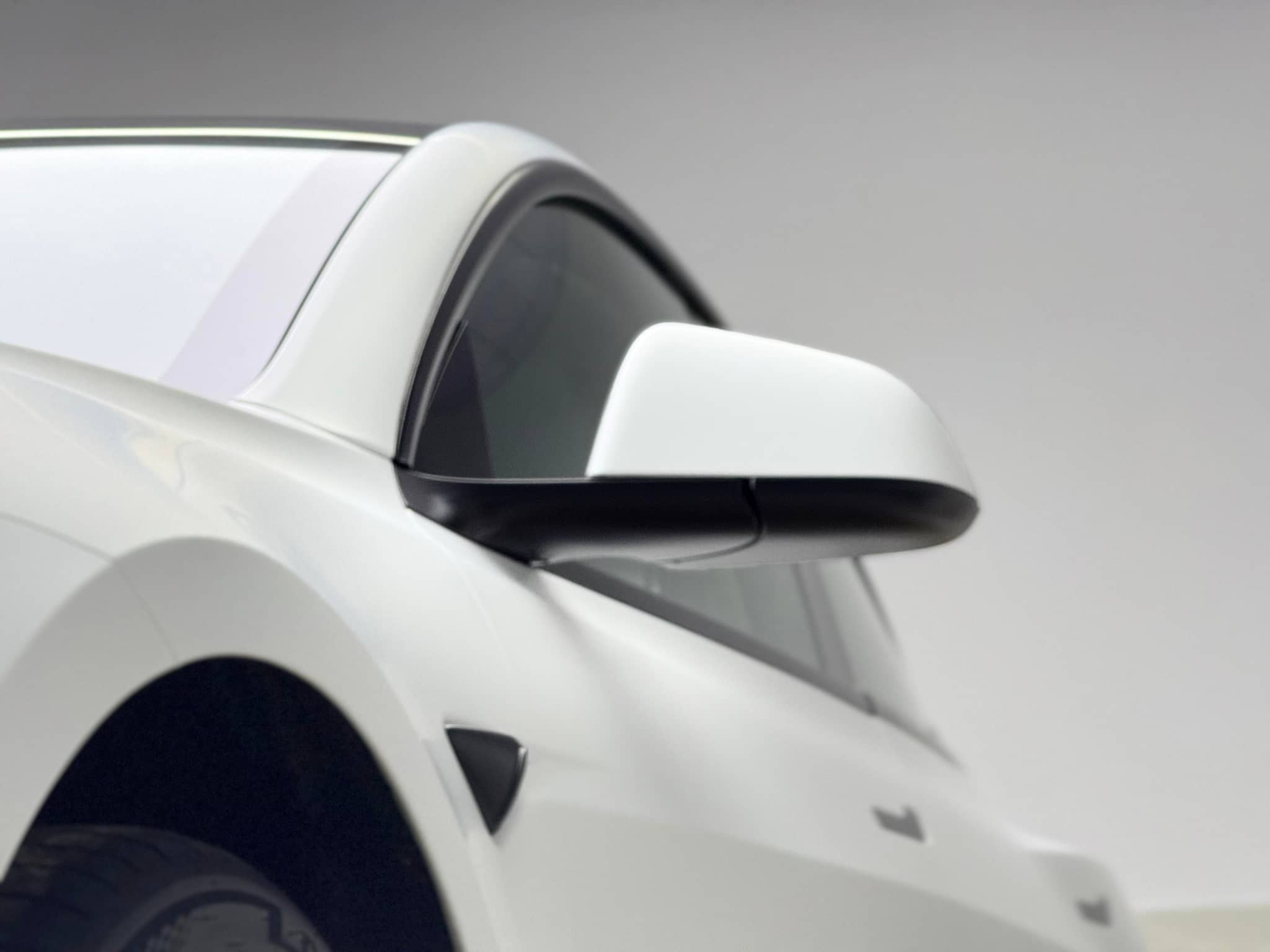 White Tesla side mirror and door panel wrapped using Pre-cut Tesla Vinyl Wrap Kit by WrapBug