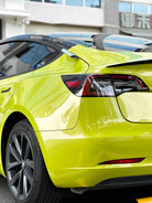Bright yellow Tesla Model 3 wrapped with pre-cut Tesla vinyl wrap kit by WrapBug showing rear side view