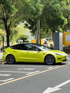 Tesla Model 3 wrapped in bright yellow using Pre-cut Tesla Vinyl Wrap Kit parked on city street