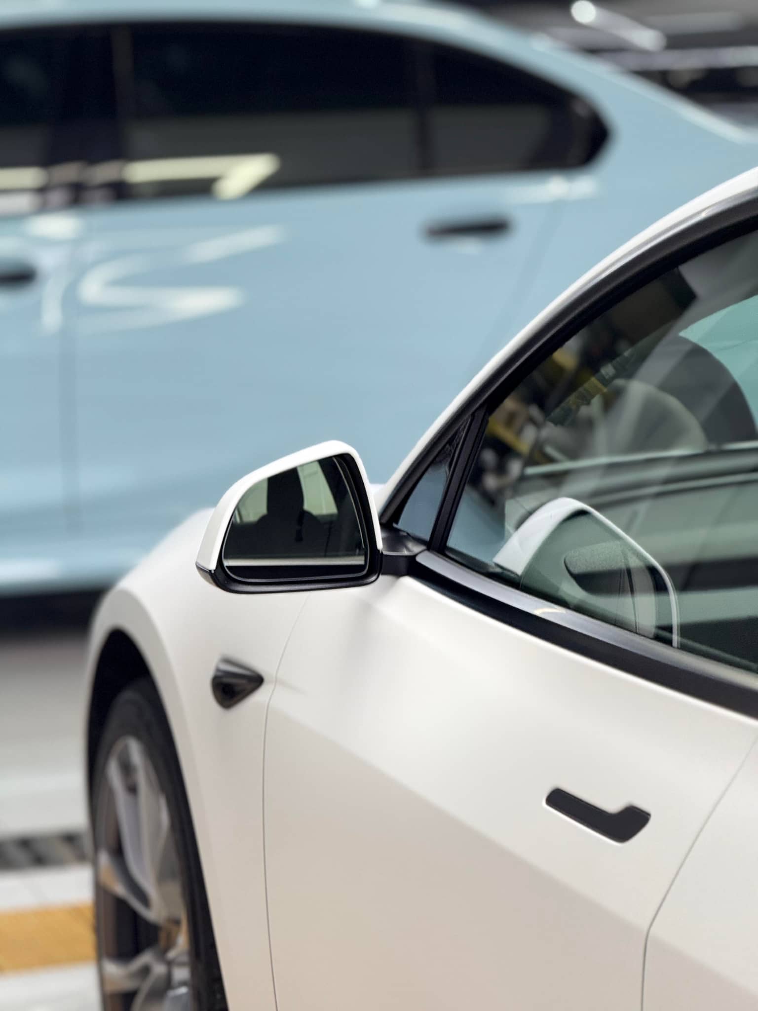 Close-up of white Tesla car showcasing the smooth finish of a Pre-cut Tesla Vinyl Wrap Kit by WrapBug