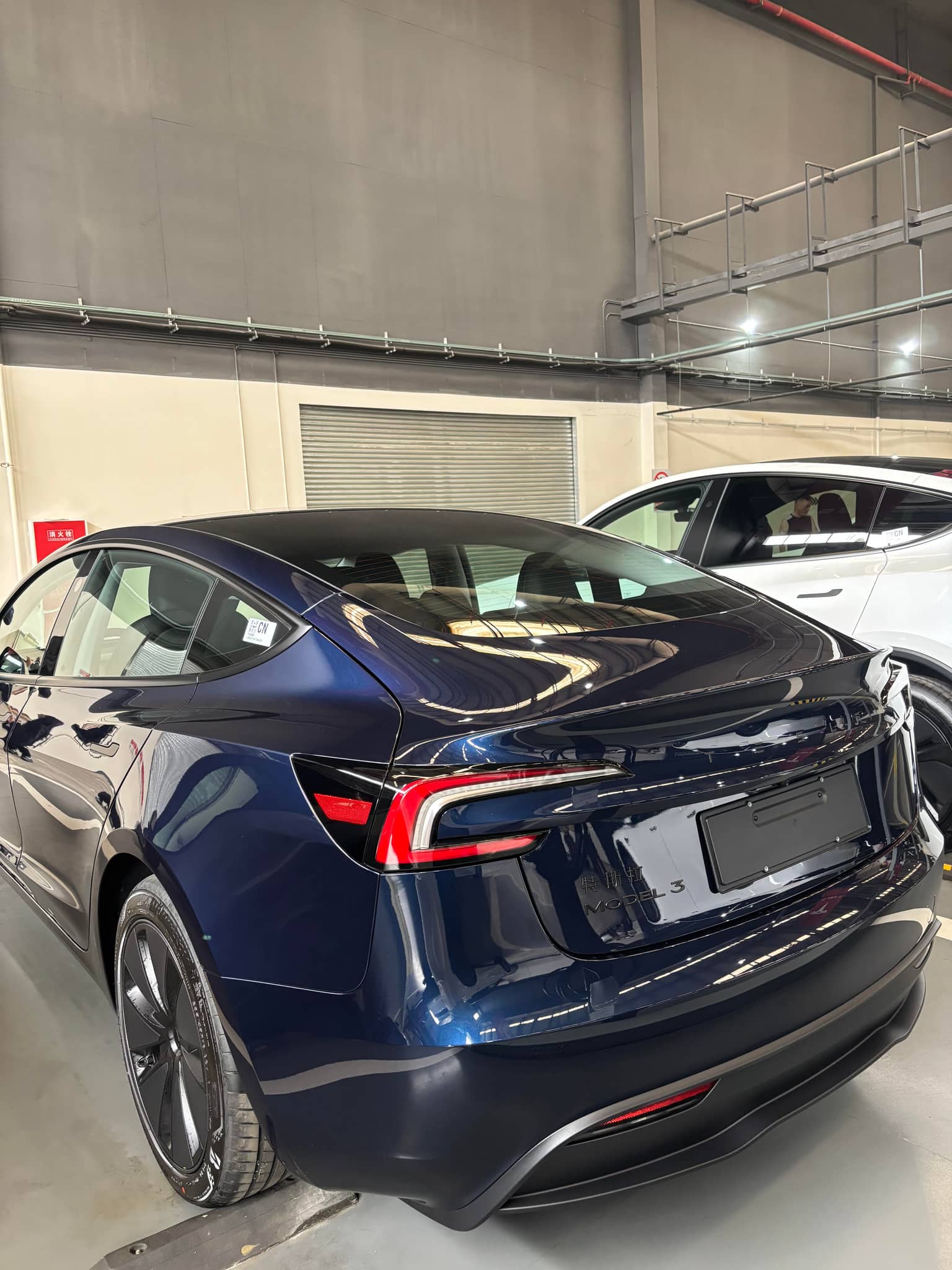 Blue Tesla Model 3 with a glossy finish showcasing the Pre-cut Tesla Wrap Kit by WrapBug in a garage