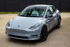Silver Tesla Model Y electric SUV parked on tiled ground with black alloy wheels
