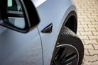 Close-up of light blue car's front wheel and side mirror with WrapBug paint protection film applied
