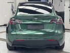 Green Tesla Model Y rear view wrapped with a Pre-cut Tesla Wrap Kit from WrapBug in a garage